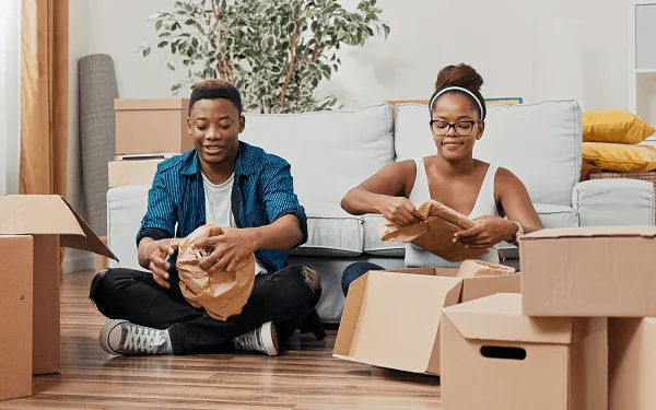 Two people unpacking moving boxes in a bright living room